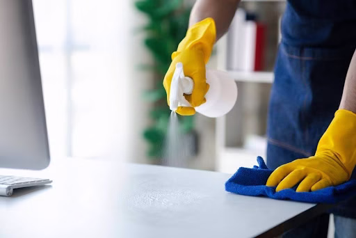 Person Cleaning a desk with marigolds and a microfibre cloth